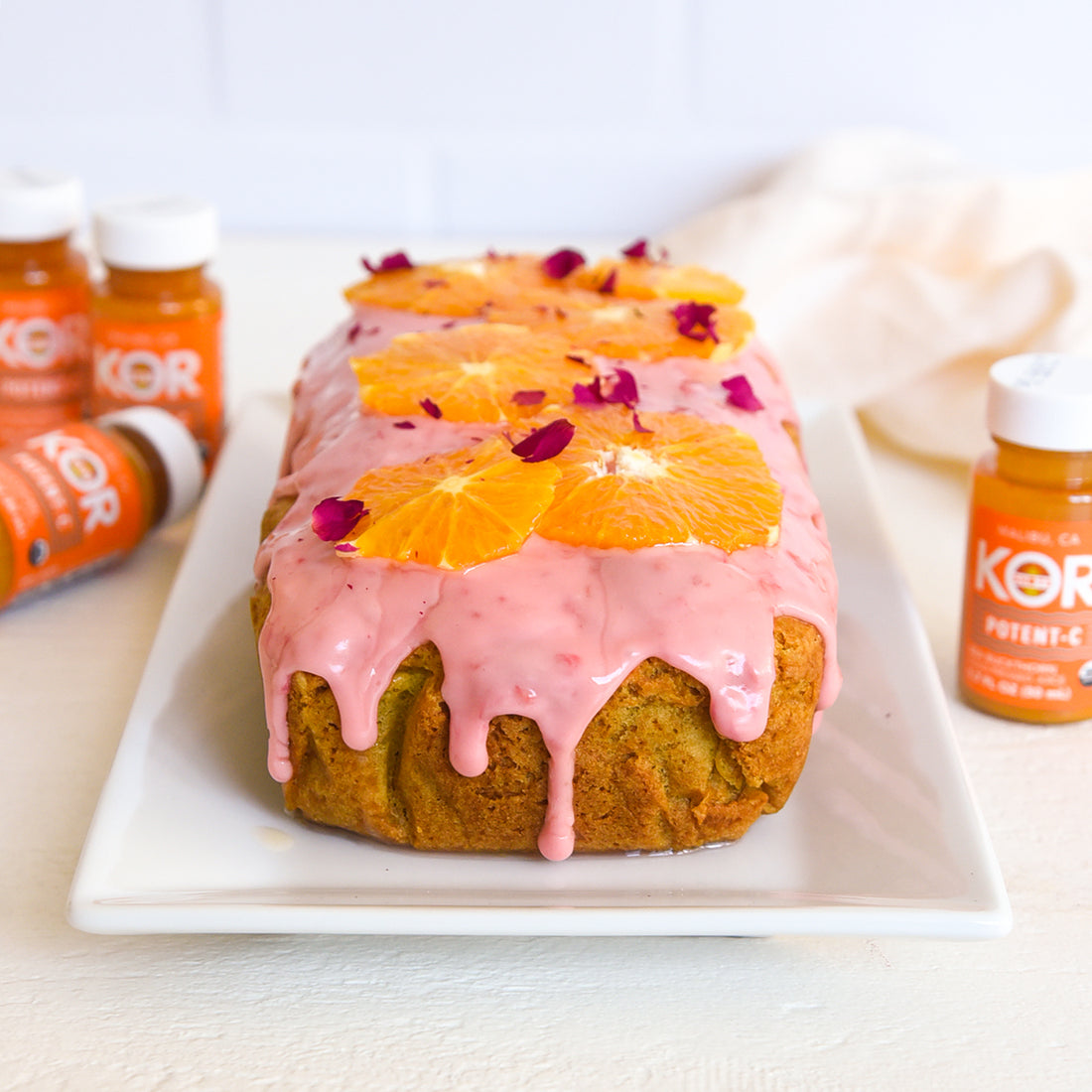 vegan citrus baked dessert loaf on a white background with potent-c shots 