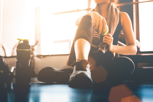 girl resting at a gym with water bottle and towel