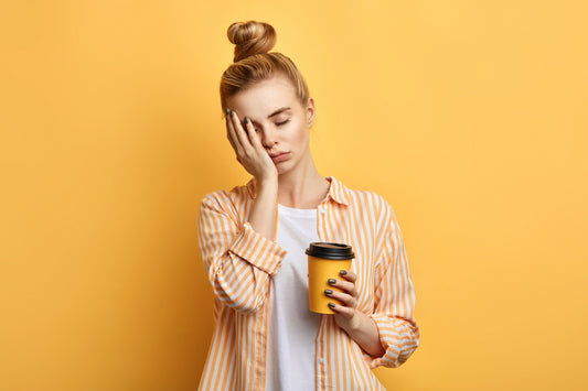 tired woman with coffee in front of a yellow background