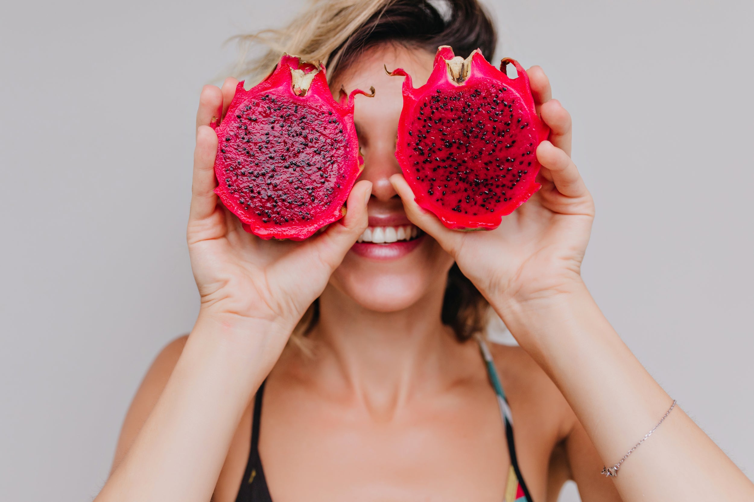 woman holding pink dragon fruit
